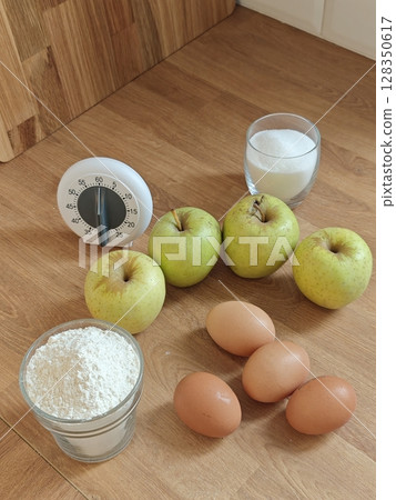 Baking with crisp green apples and fresh eggs on a wooden kitchen countertop 128350617
