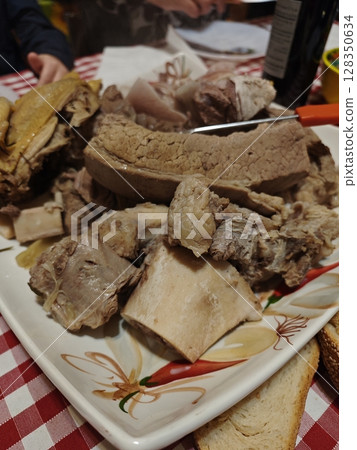 Savoring a traditional feast with tender meat and rustic flavors at a family gathering in a cozy kitchen Savoring a traditional feast with tender meat and rustic flavors at a family gathering in a cozy kitchen 128350634