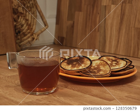 Delightful afternoon with homemade pancakes and aromatic tea on a cozy wooden table 128350679