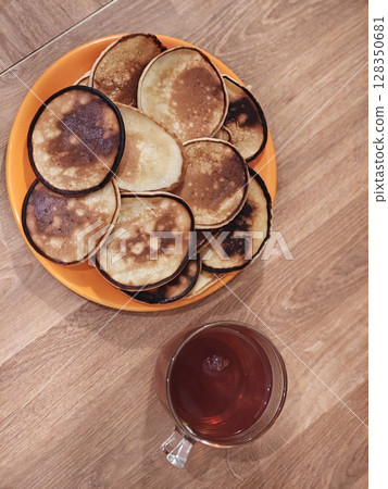 Delicious homemade pancakes served with a warm cup of tea on a wooden table 128350681