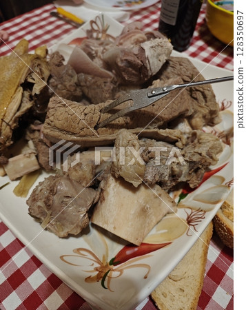 Tender cuts of savory meat served on a decorative platter with warm, inviting textures and colors, perfect for a hearty gathering 128350697
