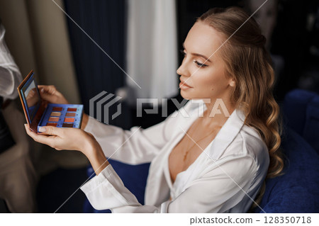 a beautiful blonde with long hair makes makeup. a beautiful blonde with long hair makes makeup. 128350718