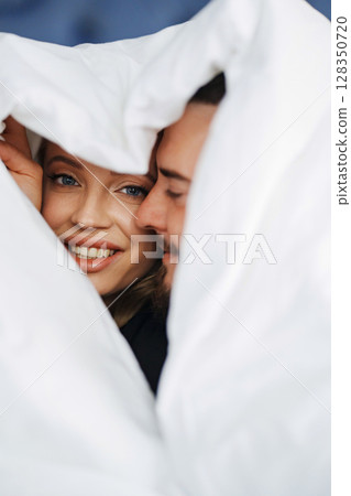 A man and a woman under the blanket on a bed. A man and a woman under the blanket on a bed. 128350720
