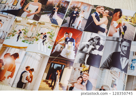 Printed wedding photos laid out on a wooden surface. 128350745