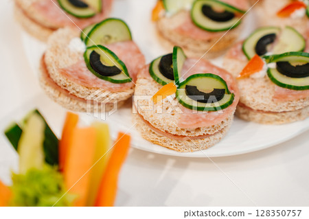 round kid sandwiches in the form of an owl on the served festive table 128350757