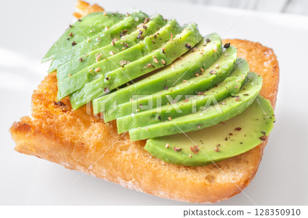 Toasted ciabatta sandwich with sliced avocado served on a clean plate 128350910