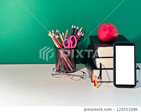 A textured background concept for learning featuring a stack of books, a red apple, a smartphone,  128351096