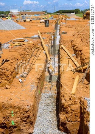 Workers are preparing trench for foundation work at busy construction site during works day 128352734