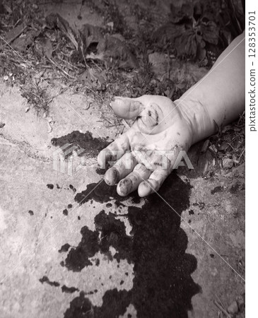 A man's hand in blood lies on the ground 128353701