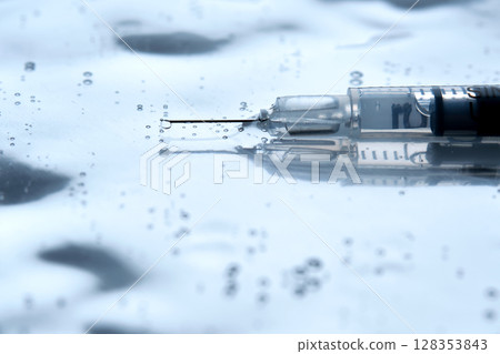 The texture of a cosmetic preparation and a syringe for injection on a blue background. 128353843