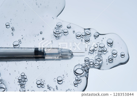 A syringe for injection in an appetizing drop with bubbles. Blue steel background. 128353844