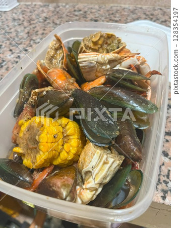 Close-up of a flavorful seafood boil featuring crab, mussels, shrimp, and corn on the cob. Close-up of a flavorful seafood boil featuring crab, mussels, shrimp, and corn on the cob. 128354197