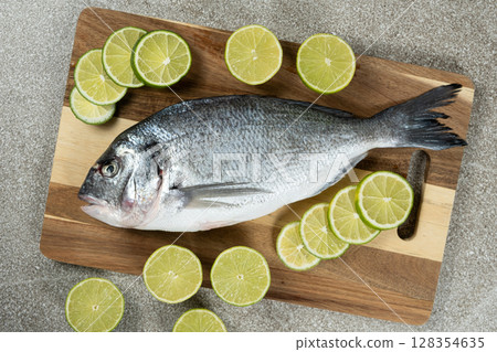 Raw Uncooked Dorado Fish with Fresh Sliced Lime Ready to Cook. 128354635