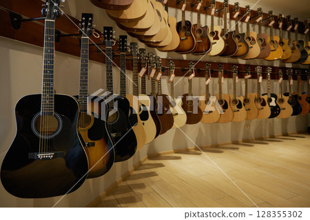 A large assortment of guitars is beautifully hanging on a wall A large assortment of guitars is beautifully hanging on a wall 128355302