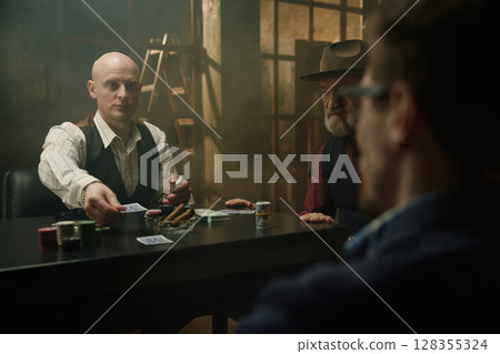 Intense poker and card game in a smoky room between male company 128355324
