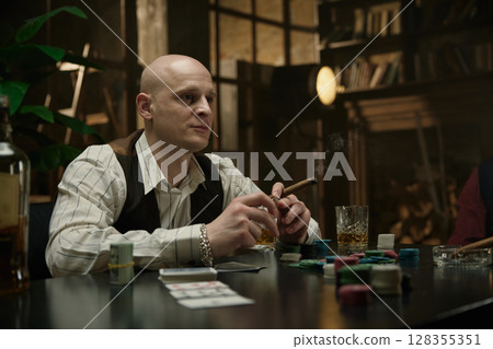 Man drinking whiskey at a poker table Man drinking whiskey at a poker table 128355351