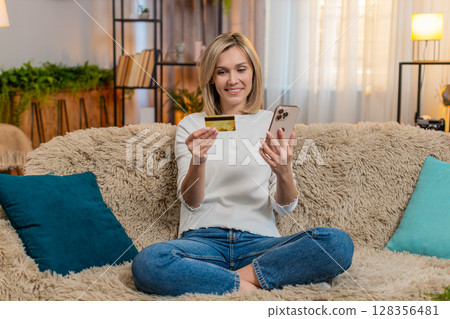 Adult woman shopping online at home with smartphone credit card satisfaction while confirming order Adult woman shopping online at home with smartphone credit card satisfaction while confirming order 128356481