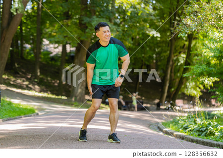 Japanese runner athlete man with muscle pain in park trauma injury while jogging leg muscle cramp 128356632