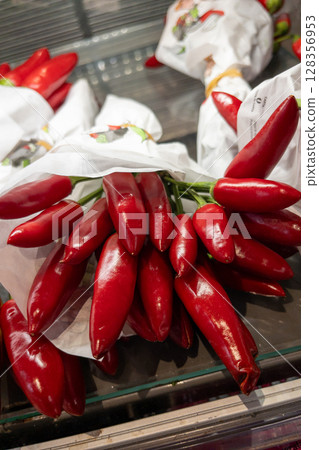 Fresh red chili peppers bundled in white paper, showcasing vibrant colors and natural textures 128356953