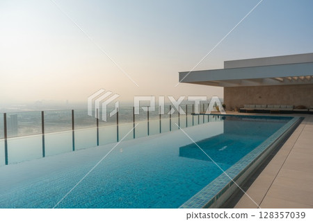 Modern rooftop swimming pool with stunning city skyline view and clear blue water reflections 128357039