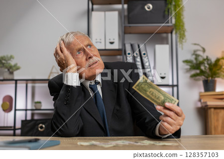Caucasian senior businessman in suit counting cash banknotes insufficient amount of money at home 128357103