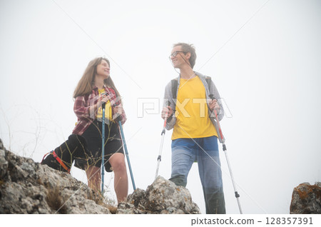 Active Couple Hiking in the Mountains on a Foggy Morning Embracing Outdoor Adventure 128357391