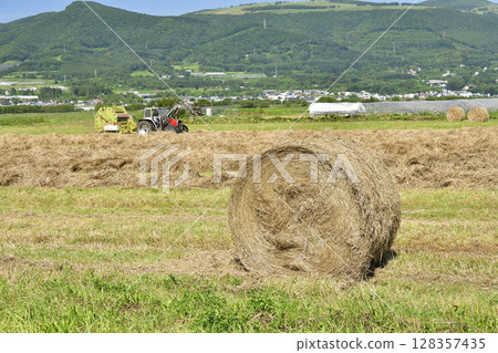 Photographing the work of making hay rolls in Hokuto, Hokkaido in summer Photographing the work of making hay rolls in Hokuto, Hokkaido in summer 128357435