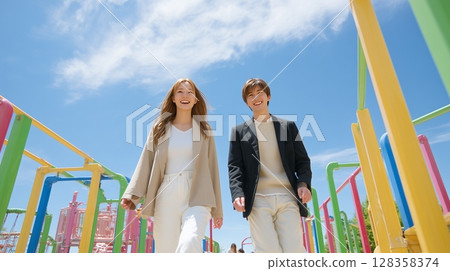 Young couple playing on playground equipment in the park 128358374