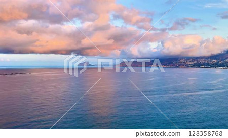An absolutely breathtaking and stunning view of the vast ocean at sunset, showcasing vibrant clouds and serene waters 128358768