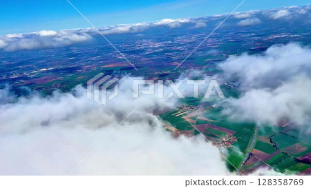 Stunning aerial footage brilliantly showcasing expansive green fields and fluffy clouds under a bright blue sky Stunning aerial footage brilliantly showcasing expansive green fields and fluffy clouds under a bright blue sky 128358769