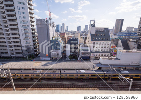 [Japan] View of the cityscape of Tokyo's 23 wards from a high-rise building and a JR Sobu Line train with a yellow line 128358960