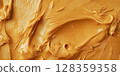Rich and creamy peanut butter is spread evenly across a textured surface, showcasing its golden color and enticing consistency, perfect for sandwiches, baking, or enjoying straight from the jar. 128359358