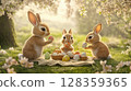 Three adorable rabbits gather around a picnic blanket under blooming trees, happily painting colorful Easter eggs. The sun shines softly, creating a joyful atmosphere filled with spring vibes. 128359365