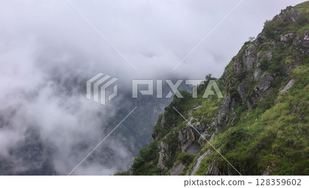 Misty Mountain Landscape with Lush Greenery and Rocky Cliffs 128359602