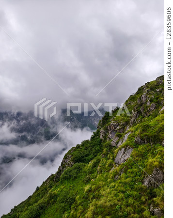 Misty Mountain Valley with Lush Cliffside Forest 128359606
