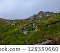Rocky Green Hillside with Scenic Cliff View Under Overcast Sky 128359660