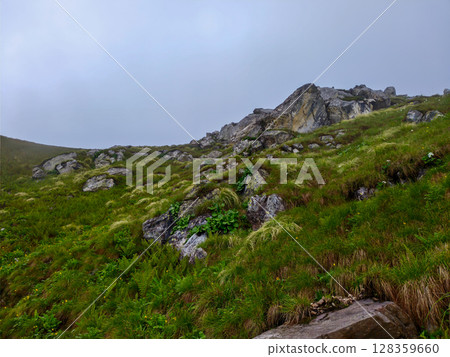 Rocky Green Hillside with Scenic Cliff View Under Overcast Sky 128359660