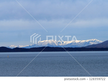 In early winter, the snow-capped Mt. Iide shines white across Lake Inawashiro. The pale blue monotone world is impressive and beautiful. 128359722