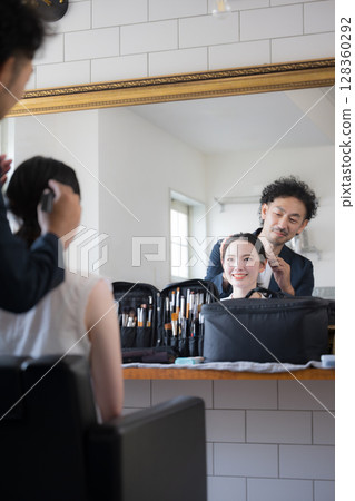 Men and women with hair and makeup holding makeup brushes, image of makeup, looking in the mirror Men and women with hair and makeup holding makeup brushes, image of makeup, looking in the mirror 128360292