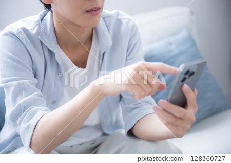 特寫鏡頭：一名戴著眼鏡的男子看著他的智慧型手機，思考和擔憂，沒有臉 128360727