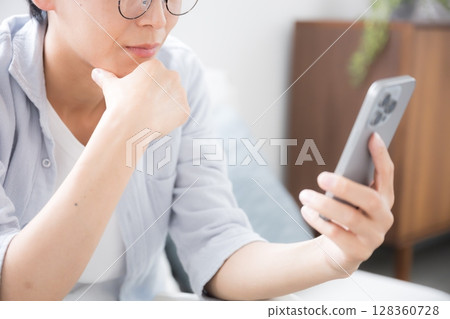 特寫鏡頭:一名戴著眼鏡的男子看著他的智慧型手機,思考和擔憂,沒有臉 特寫鏡頭:一名戴著眼鏡的男子看著他的智慧型手機,思考和擔憂,沒有臉 128360728