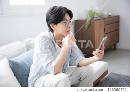 A man thinking about his smartphone 128360731
