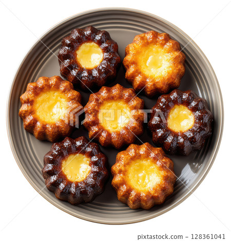 Small French Pastries Caneles de Bordeaux with Soft Custard Center and Dark Caramelized Crust on Plate 128361041