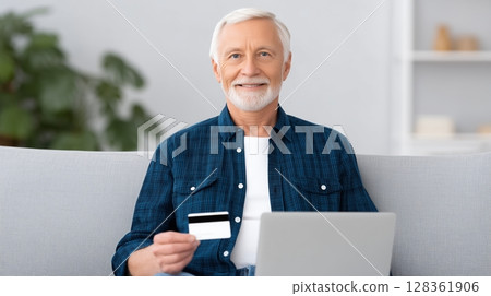 Social security benefits concept, A senior man holding a credit card while using a laptop at home. 128361906