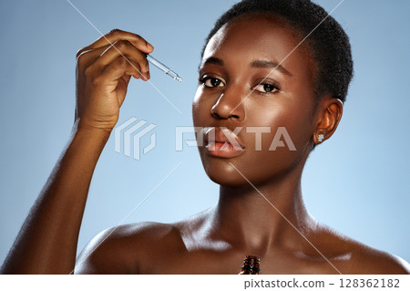 Woman applying skincare serum with dropper in a softly lit studio setting Woman applying skincare serum with dropper in a softly lit studio setting 128362182