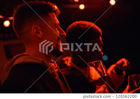 Friends enjoying drinks under warm lights during an evening gathering outdoors in a festive atmosphere Friends enjoying drinks under warm lights during an evening gathering outdoors in a festive atmosphere 128362200