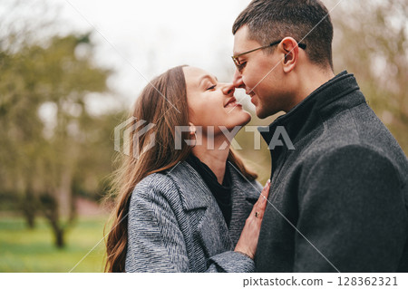 Couple enjoying a tender moment together in a serene park during a cloudy day 128362321