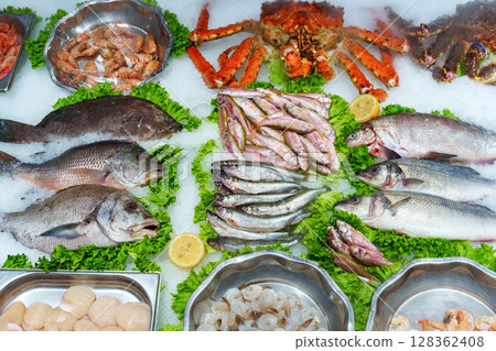 Fresh seafood display with various fish and shellfish on ice at a market Fresh seafood display with various fish and shellfish on ice at a market 128362408