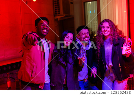 Friends enjoying a vibrant night out in a lively venue with colorful lighting in a city setting Friends enjoying a vibrant night out in a lively venue with colorful lighting in a city setting 128362428