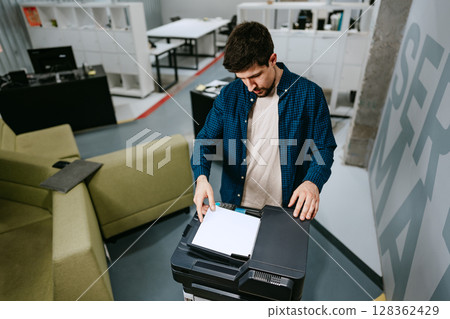Office worker using a multifunction printer to scan documents in a modern workspace during the day Office worker using a multifunction printer to scan documents in a modern workspace during the day 128362429